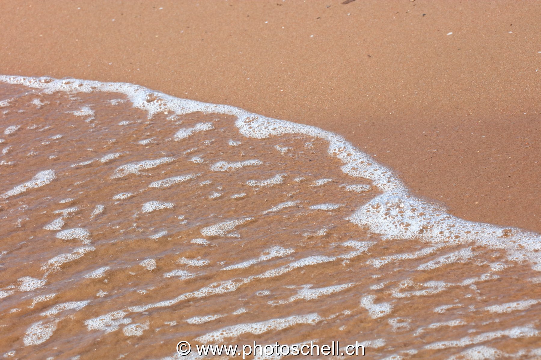 Vaguelettes s'écrasant sur la plage de sable